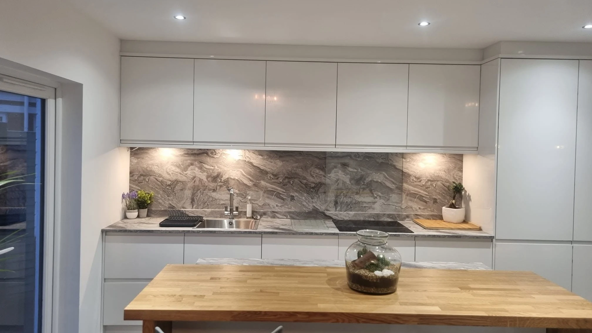 A renovated kitchen with white cabinets and a timber island