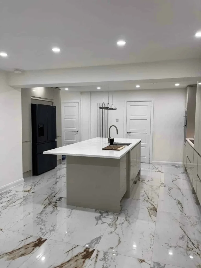 White kitchen island and gloss grey cabinets viewed from the opposite end of the room