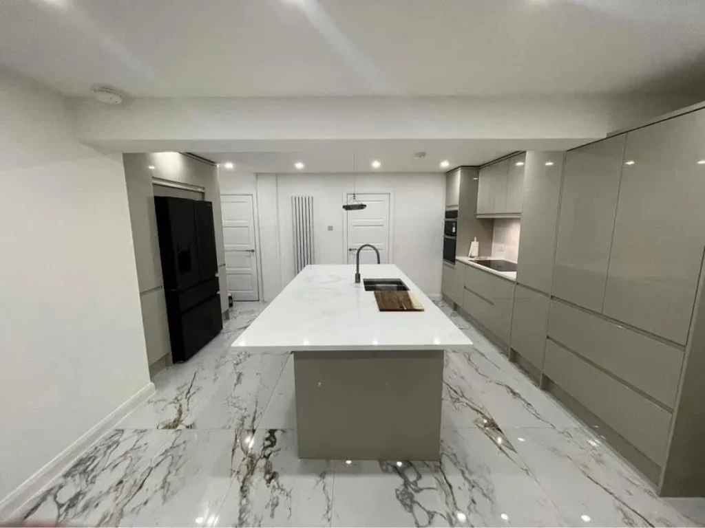 White kitchen island surrounded by gloss grey cabinets and patterned floor tiles