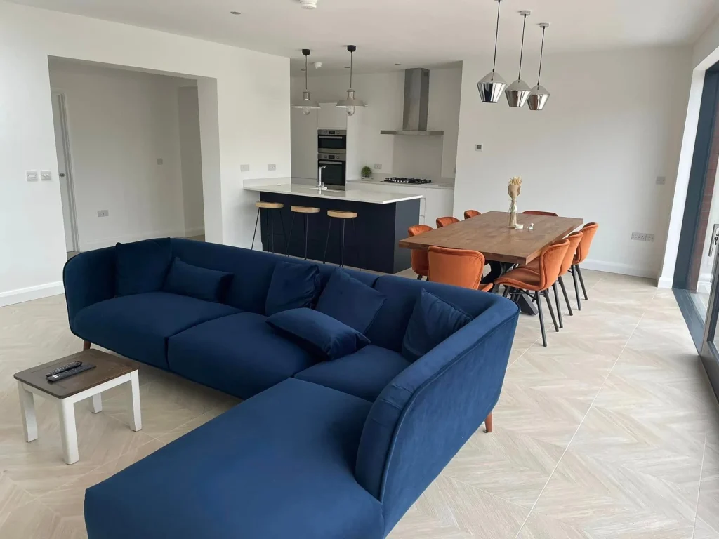 Navy sofa beside a dining table and kitchen island beneath pendant lights