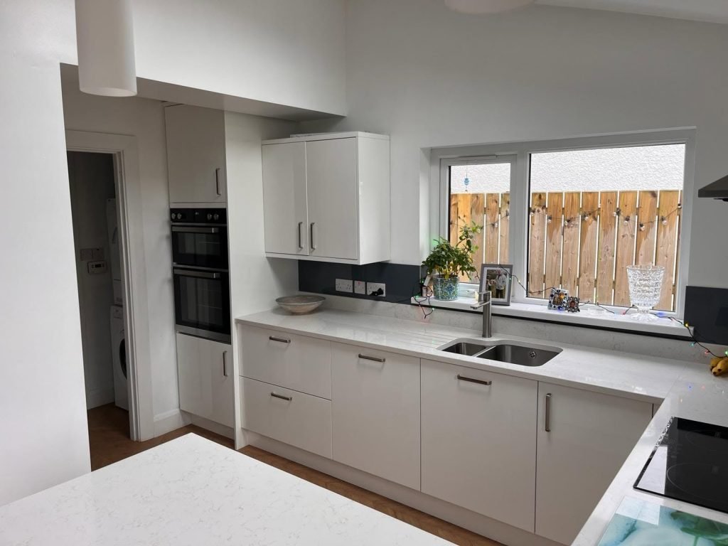 White kitchen cupboards with a sink beneath the side window