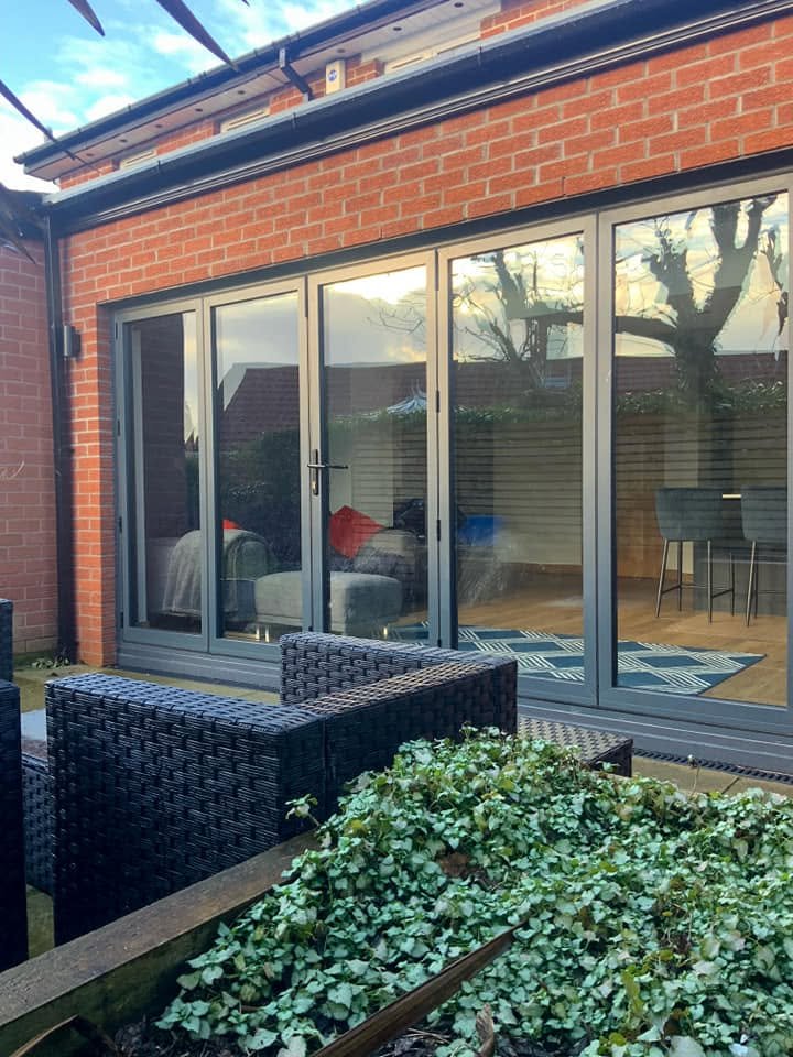 Red brick extension with wide dark bifold doors and outdoor seating