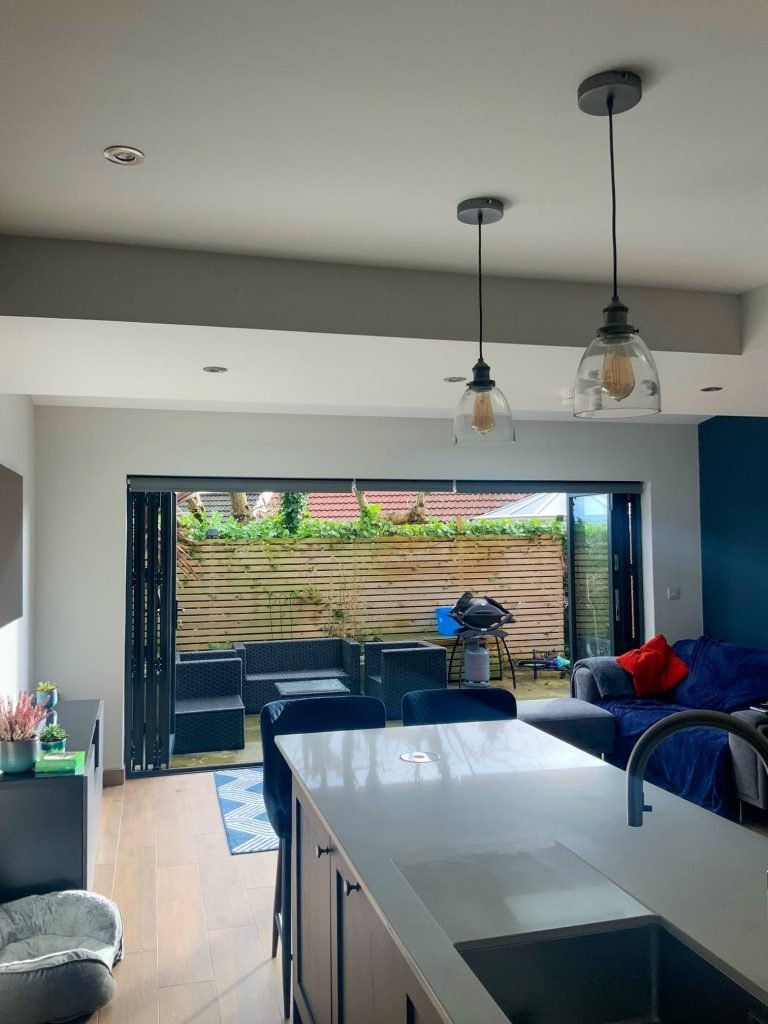View across a kitchen island towards a sitting area and open garden doors