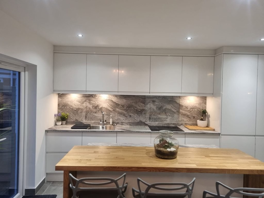 Timber breakfast bar facing the grey kitchen cabinets, sink and hob