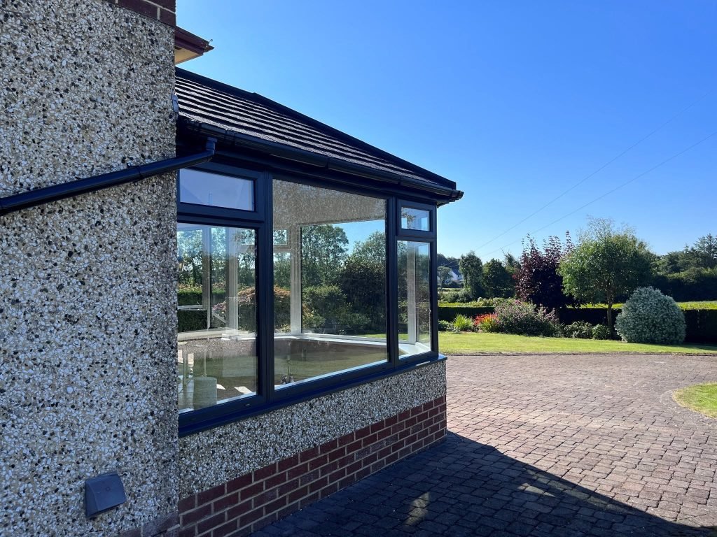 Anthracite conservatory frames and tiled roof beside the house and garden