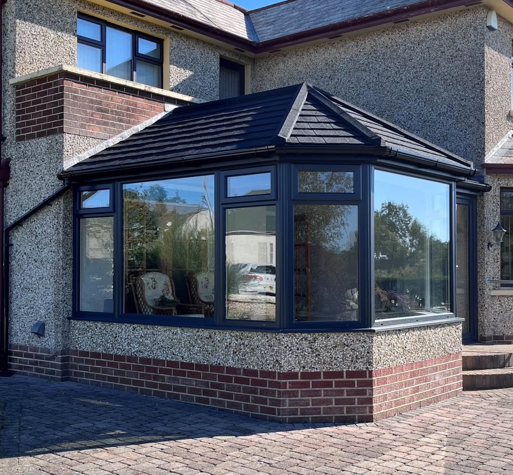 Faceted conservatory with anthracite frames, a tiled roof and red brick plinth