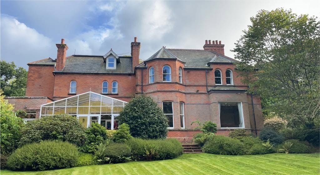 Original red brick house with a pitched conservatory before the extension