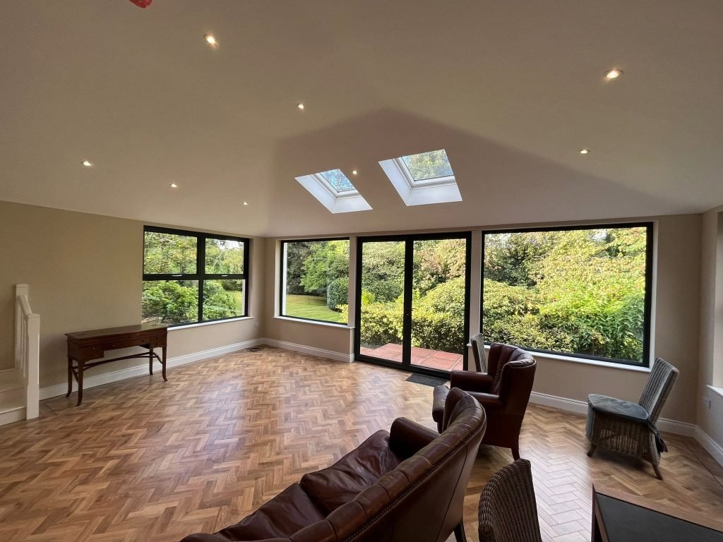 Finished living space with herringbone flooring, dark framed garden windows and two rooflights