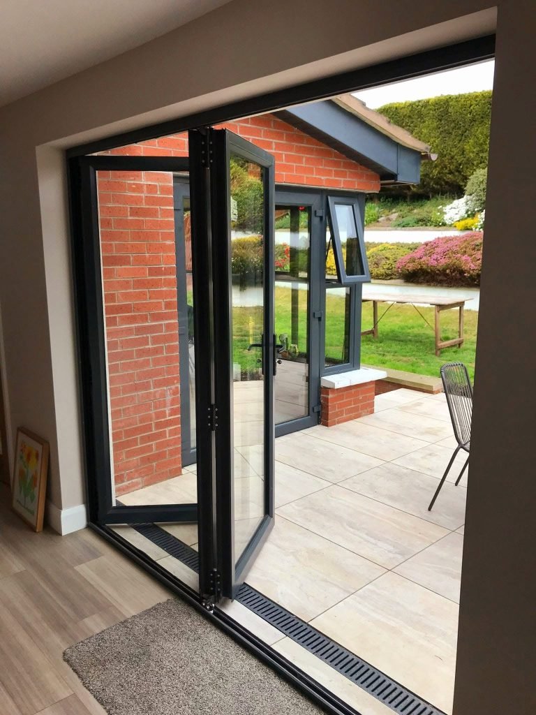 Partially opened bifold doors beside an adjoining brick sunroom