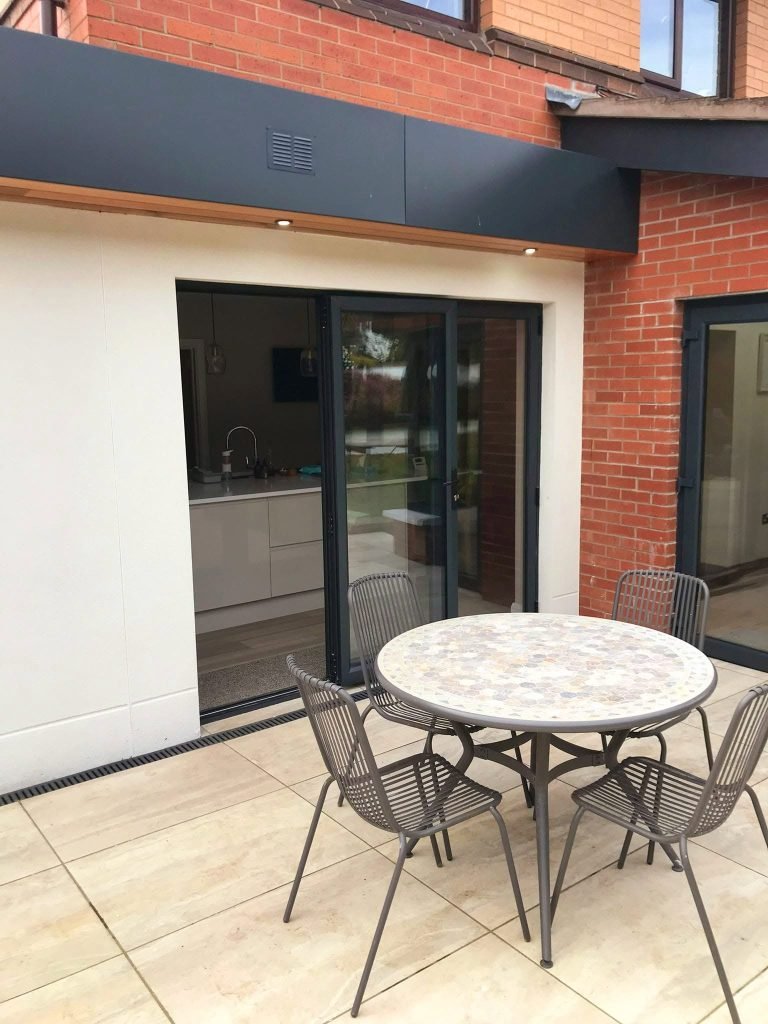Closed anthracite bifold doors beside the patio table and chairs