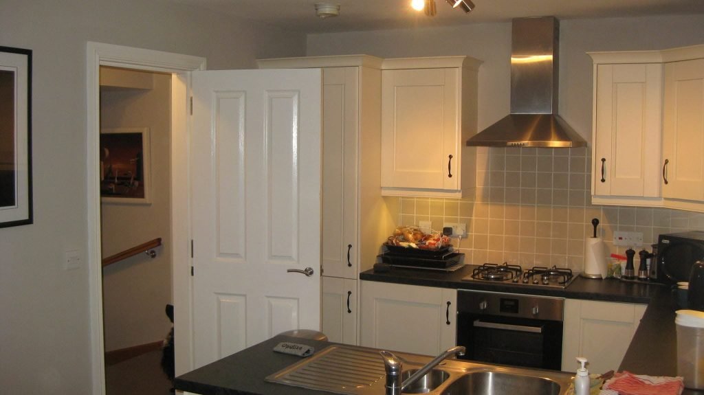 Original cream kitchen with a solid doorway to the stairs before renovation