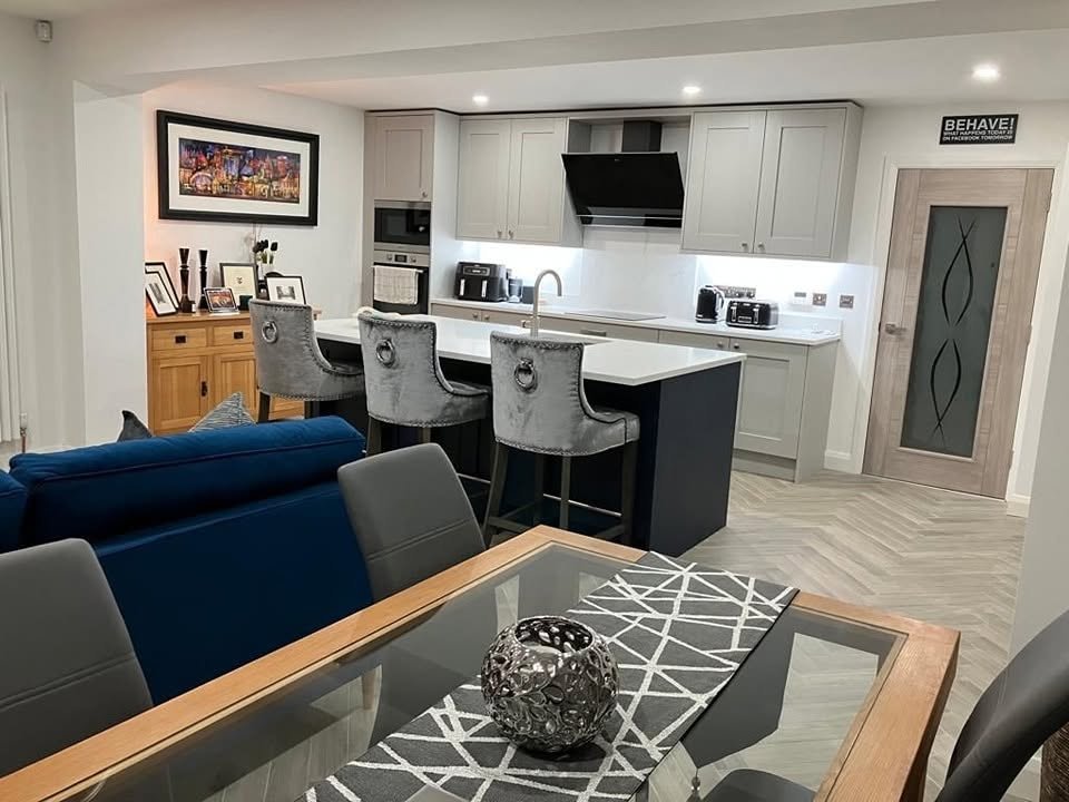 Kitchen island and three stools beside a blue sofa and dining table