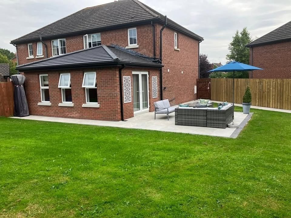 Completed brick extension with three white windows, side door and paved patio