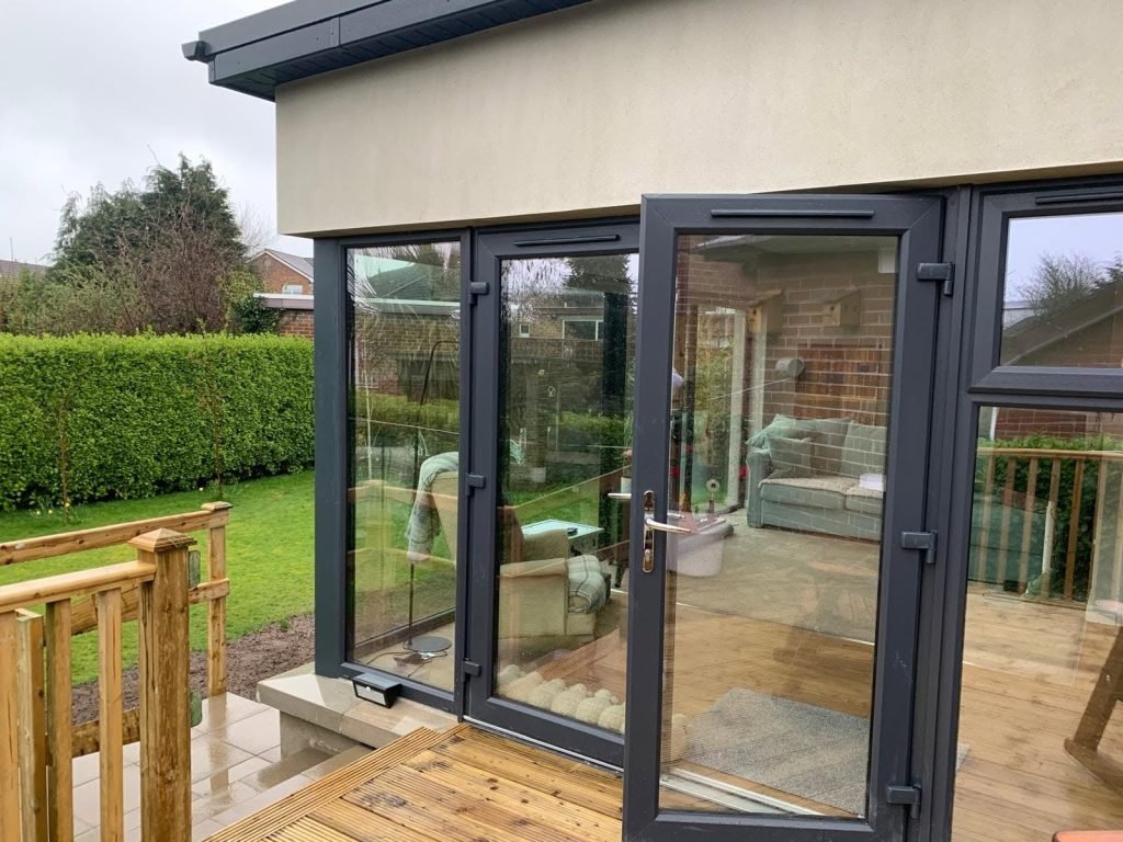 Dark framed glazed door opening onto the timber garden deck