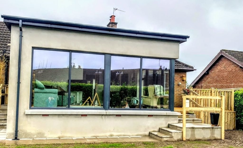 Completed white rendered extension with dark garden glazing and timber handrails
