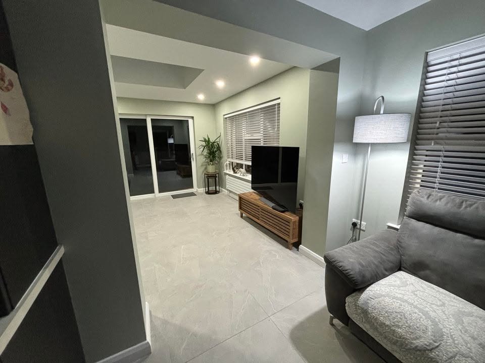Grey furnished sitting area with a wide side window and garden doors