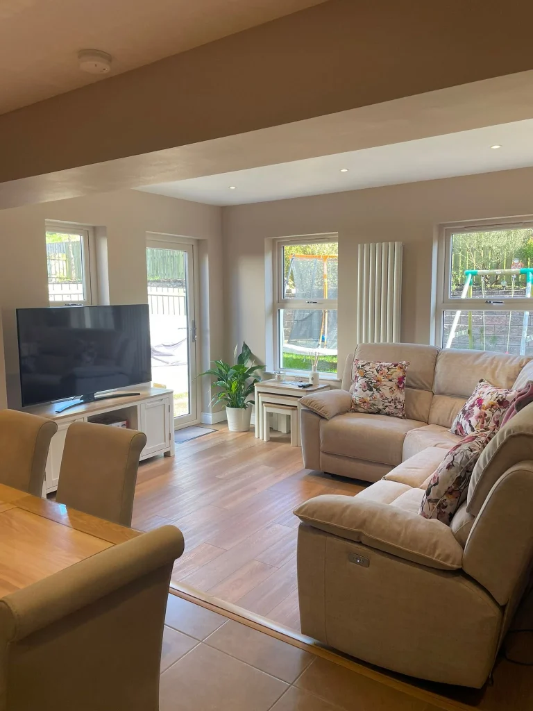 Bright furnished living area with a sofa, television and garden windows