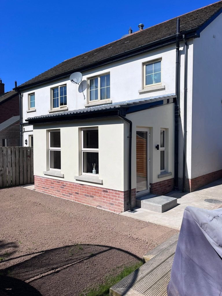 Cream rendered rear extension with two windows, a side door and red brick plinth
