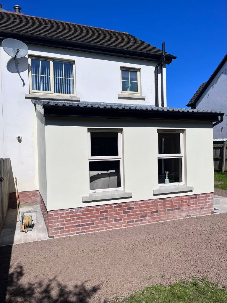 Rear view of the cream extension with paired windows and a red brick plinth