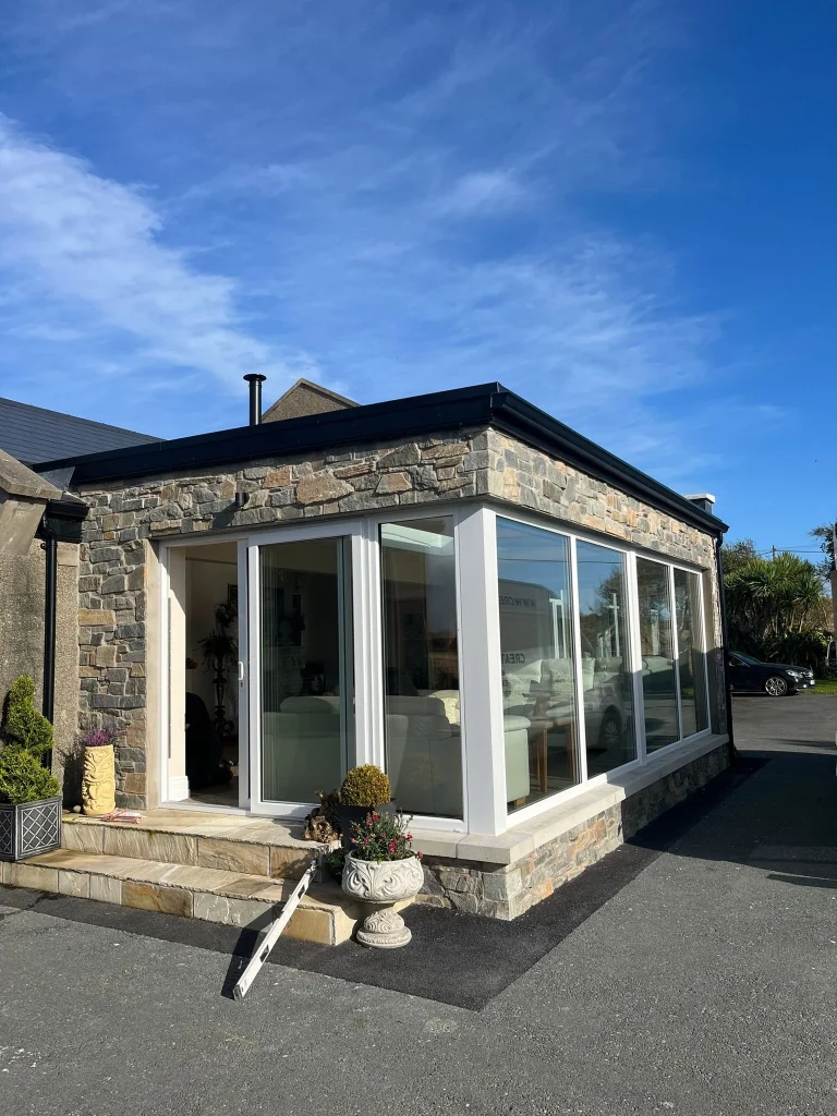 Stone clad extension with corner glazing and white sliding doors