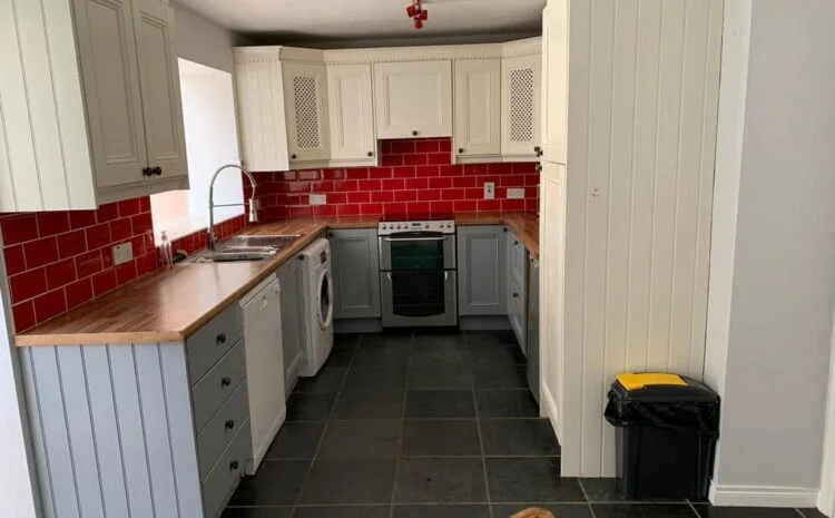 A completed grey and white kitchen with red wall tiles