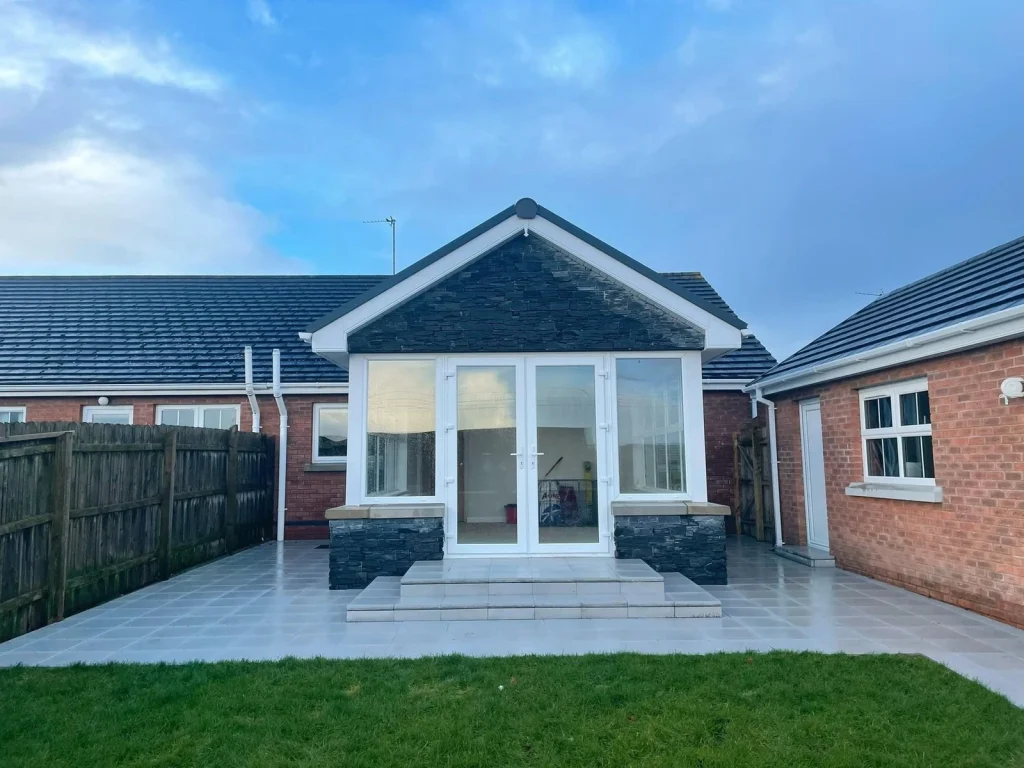 Completed stone clad sunroom opening onto a paved terrace