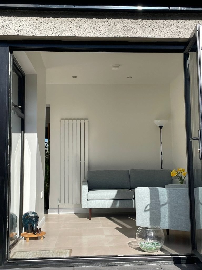 Open glazed garden doors framing the grey sofas in the Newcastle extension