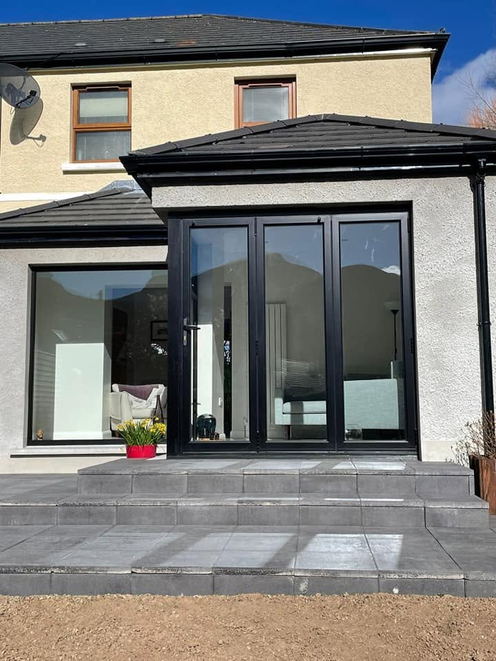 Rear exterior of the Newcastle extension with closed dark glazed doors, a broad window and paved steps