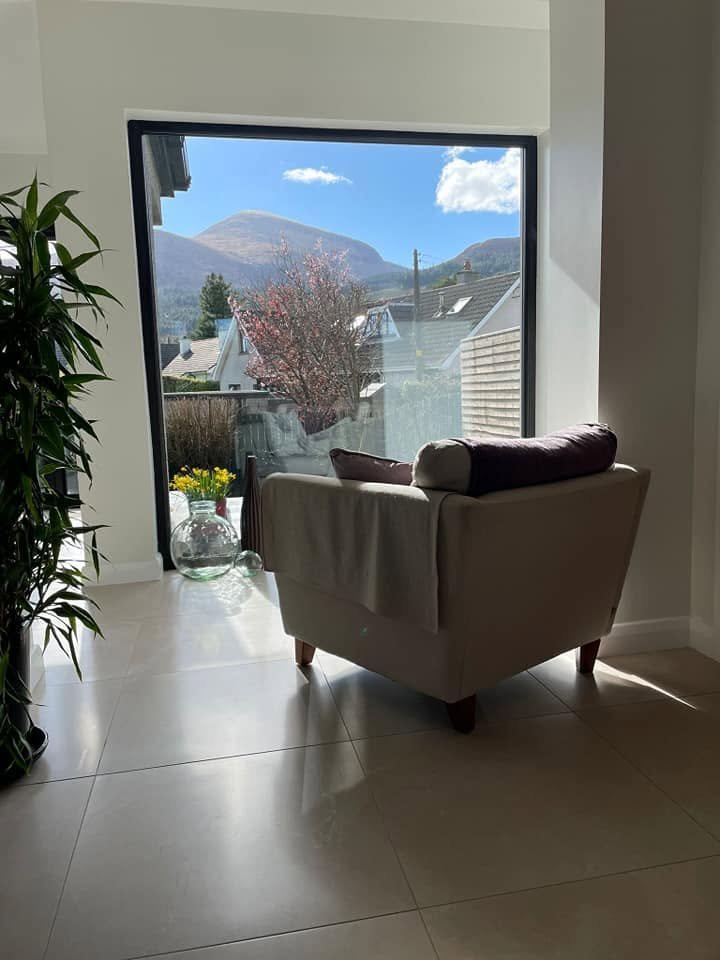 Armchair beside a broad window looking towards the Mourne Mountains in the Newcastle extension